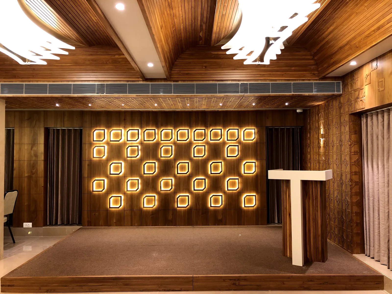 Banquet stage with illuminated feature wall and wooden ceiling at Ashirwad