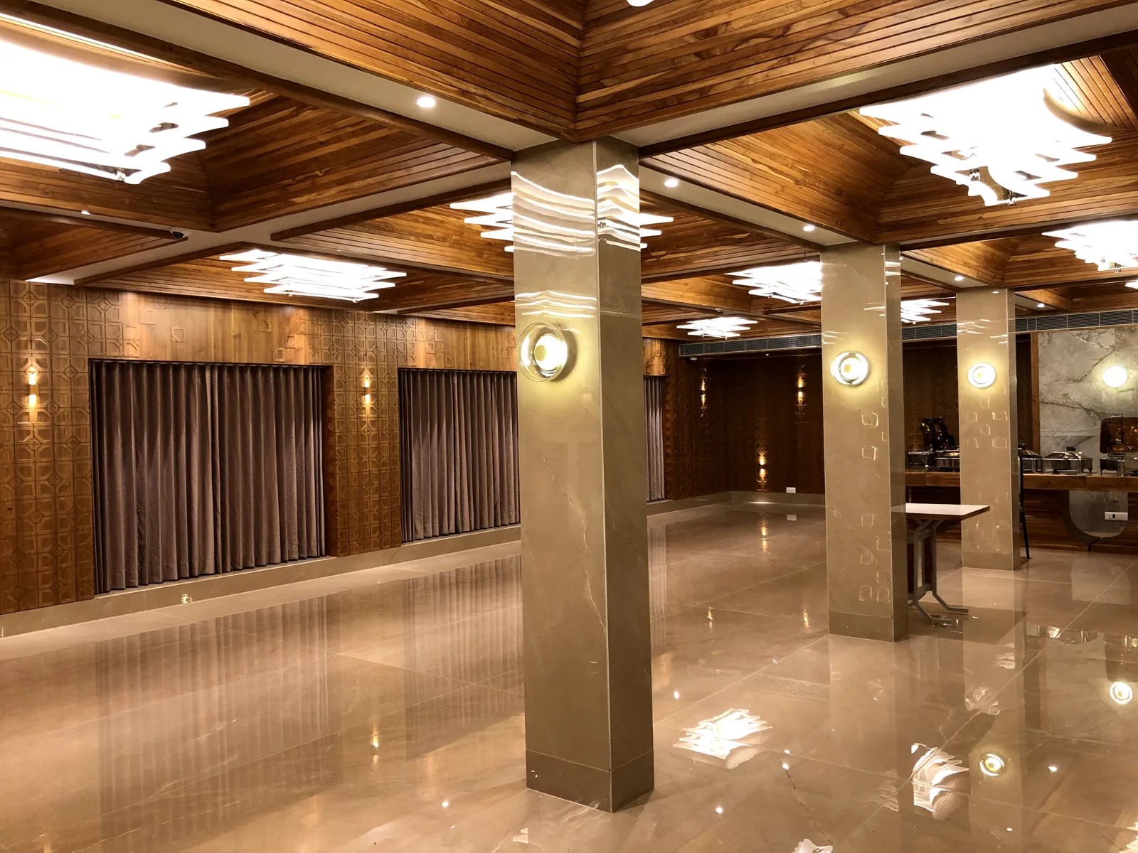 Spacious Ashirwad hall with curtained windows and wooden ceiling